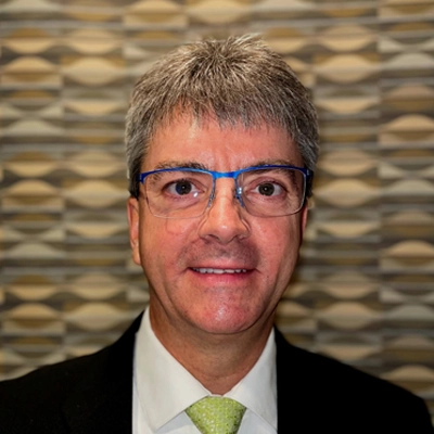 Brian Norman smiling while wearing blue glasses.